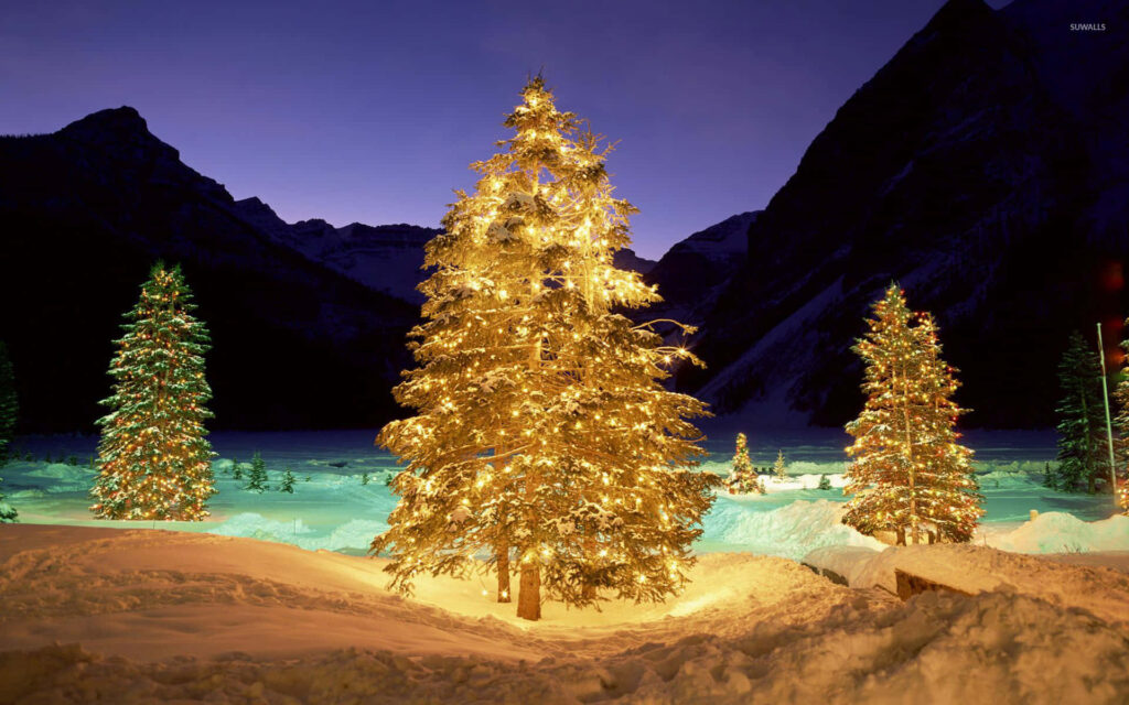 Serene Winter Scene: Glowing Christmas Tree in Snowy Mountains Wallpaper