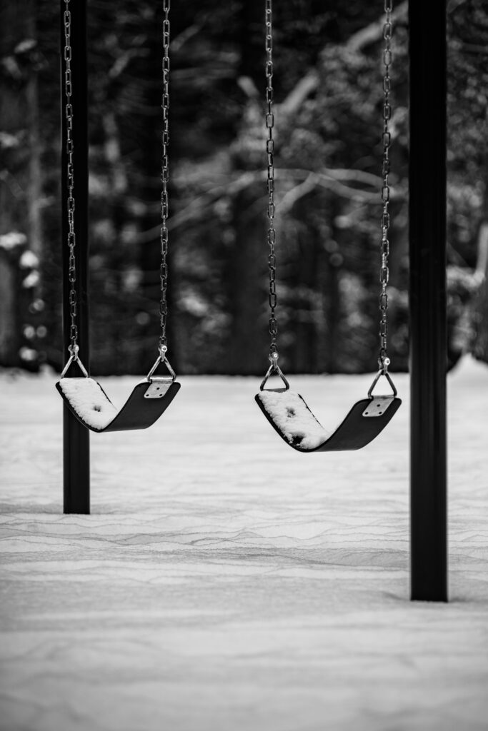 Nostalgic Black and White Winter Scene: Swings in Snowy Background Wallpaper