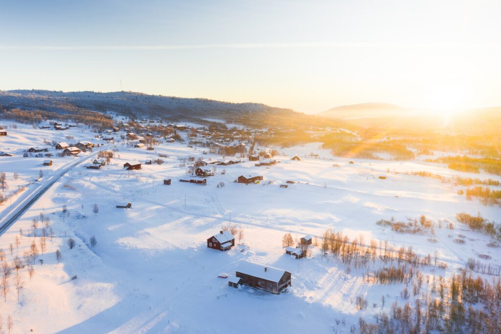 Aerial view of a peaceful winter village with snowy rooftops and warm golden sunlight fields Wallpaper