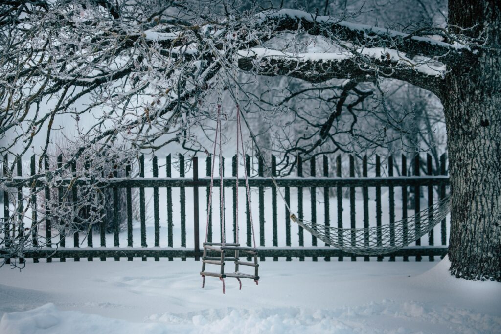 Serene winter wallpaper with rustic swing on snowy tree and wooden fence background winter scene