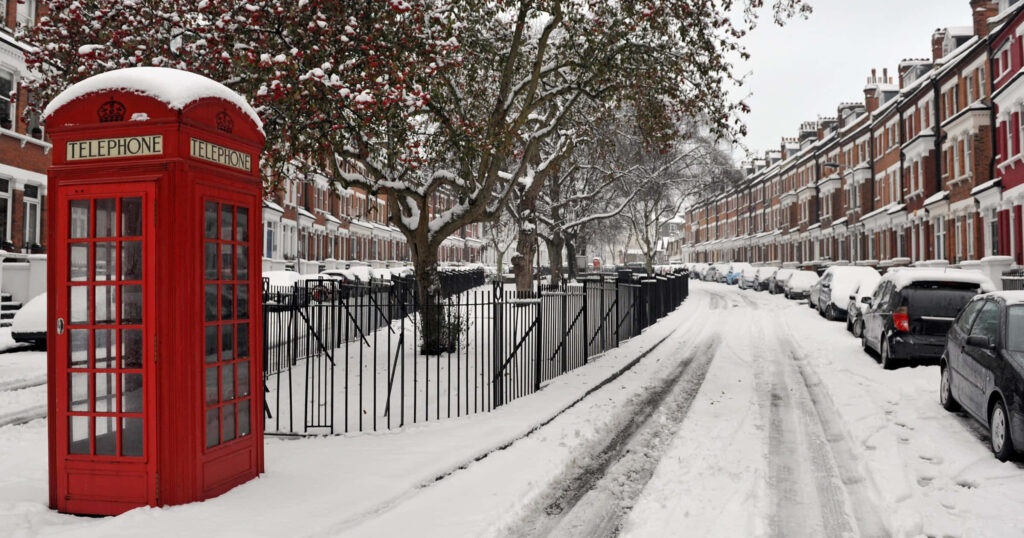 Tranquil Snow-Covered Street with Classic Homes and Red Phone Booth Wallpaper