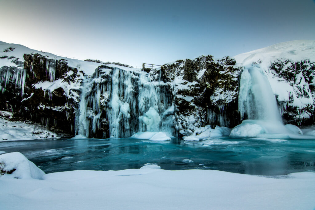 Winter waterfall cascading over icy cliffs at twilight with serene frozen blue landscape wallpaper