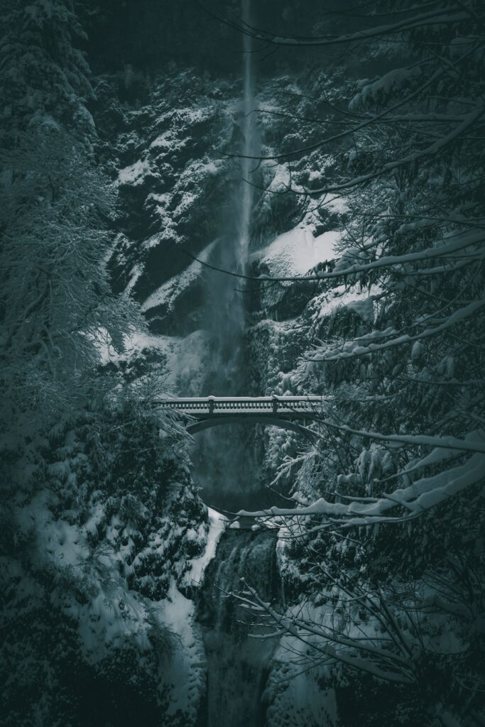 Serene winter waterfall with snow-covered trees and a picturesque bridge in an enchanted forest Wallpaper