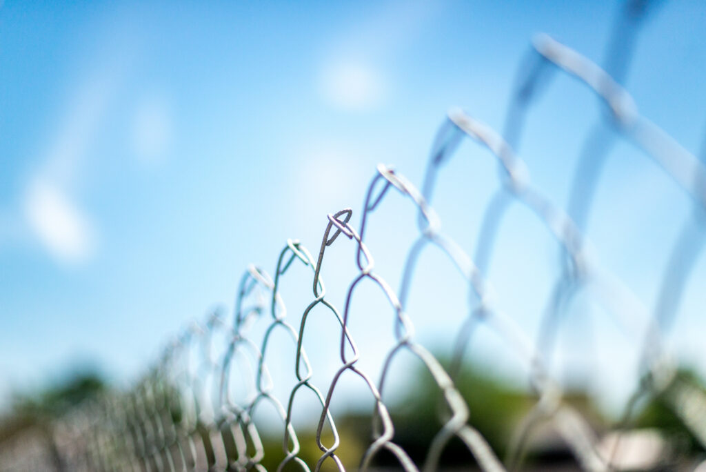 Serene Wire Grid Fence Close-Up with Soft Blue Sky - Minimalist Wallpaper