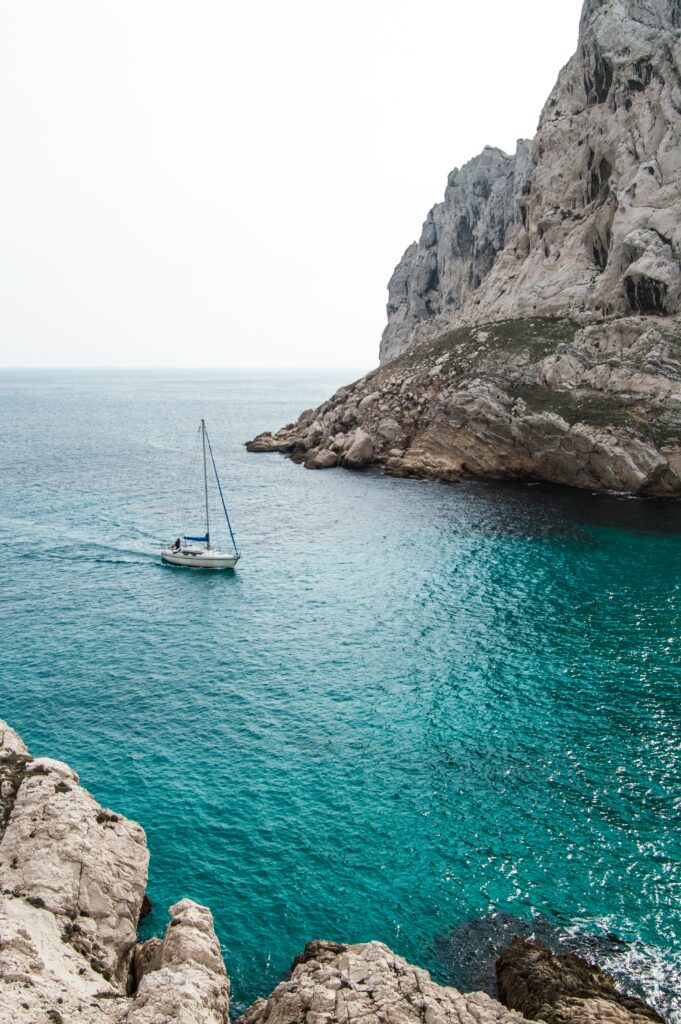 Yacht sailing on turquoise water near white rocky cliffs under bright sky serene sea wallpaper