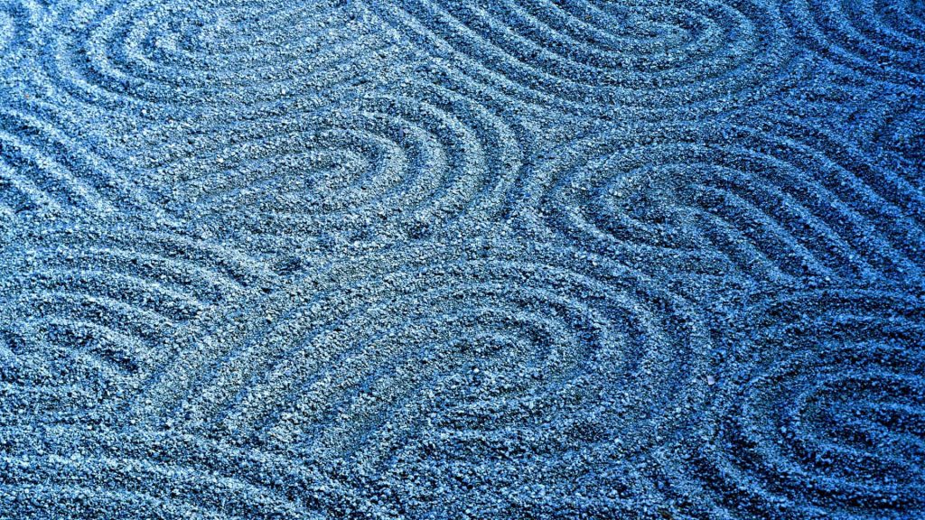 Serene Zen garden wallpaper with intricate blue sand ripples for calming desktop background