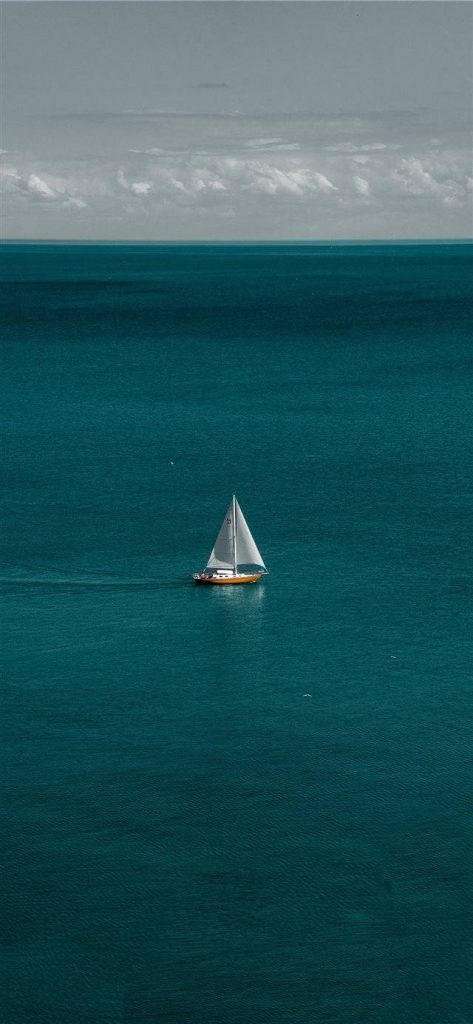 Serene iPhone wallpaper with a lone sailboat on calm turquoise waters and cloudy horizon