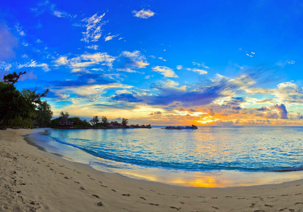 Serenity over Tropical Shores: A Captivating Sunset Wallpaper for Your Desktop