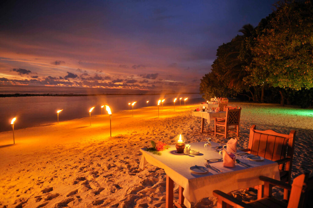 Surreal Gourmet Experience: Sunset Fine Dining amidst Flaming Torches on Pristine Maldivian Beach Wallpaper
