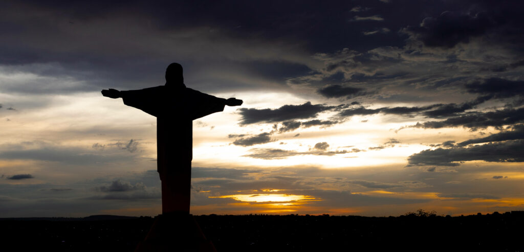 The Divine Embrace: Jesus' Silhouette Amidst a Serene Sunset Wallpaper