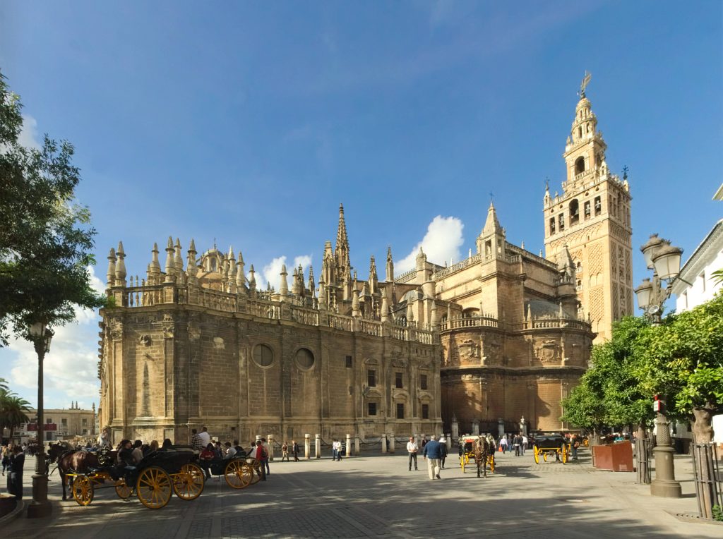 Seville Cathedral with Giralda tower horse-drawn carriages vibrant Gothic architecture Spain plaza Wallpaper