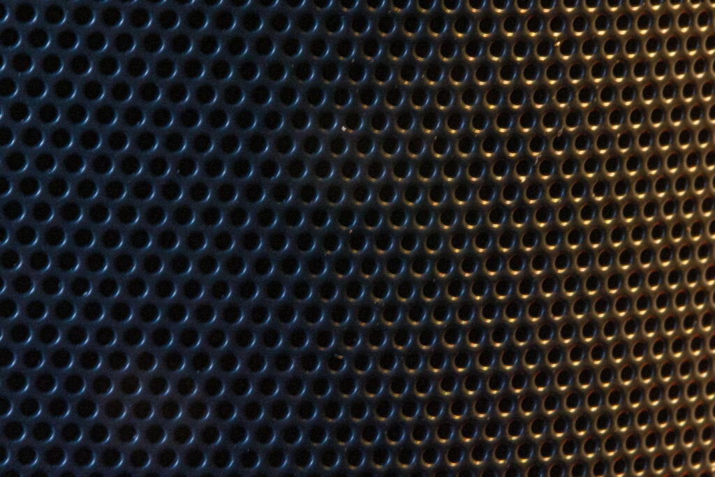 Gentle Illumination Reveals Shadows in Curved Perforated Metal Texture - Mesmerizing Background Image Wallpaper