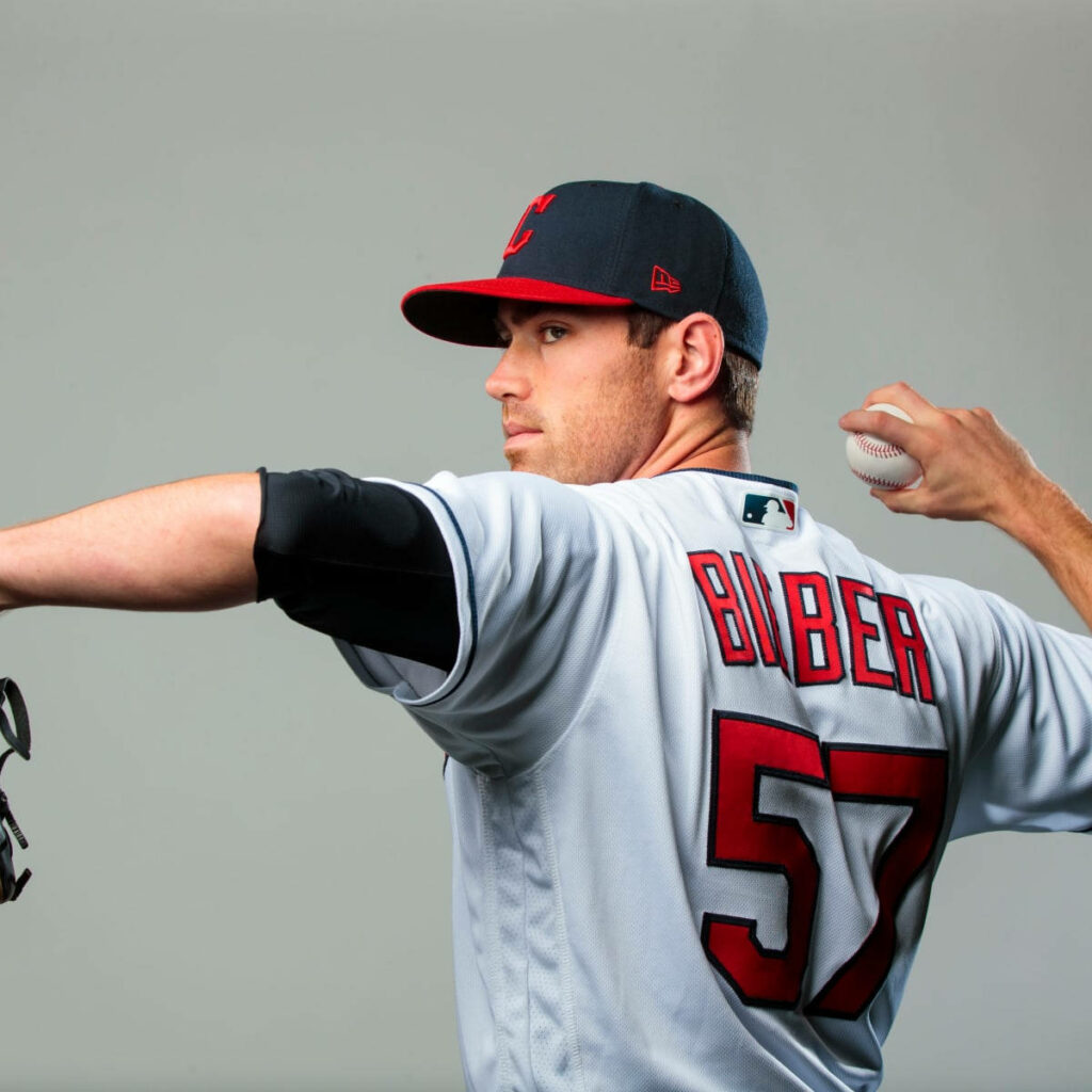 Shane Bieber Cleveland Guardians pitching in crisp white jersey with red and navy accents wallpaper