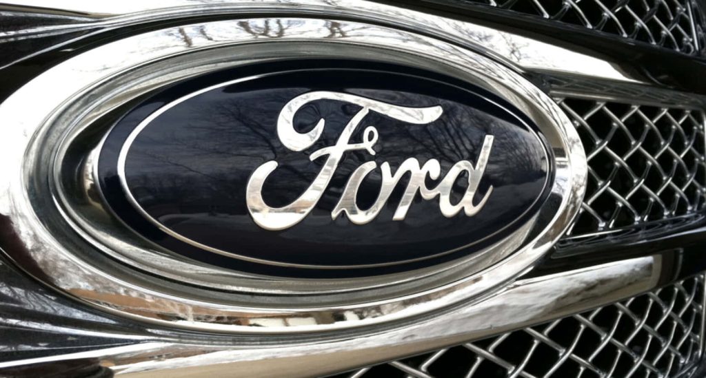 Close-up of polished chrome Ford emblem on detailed metallic grille high-resolution wallpaper