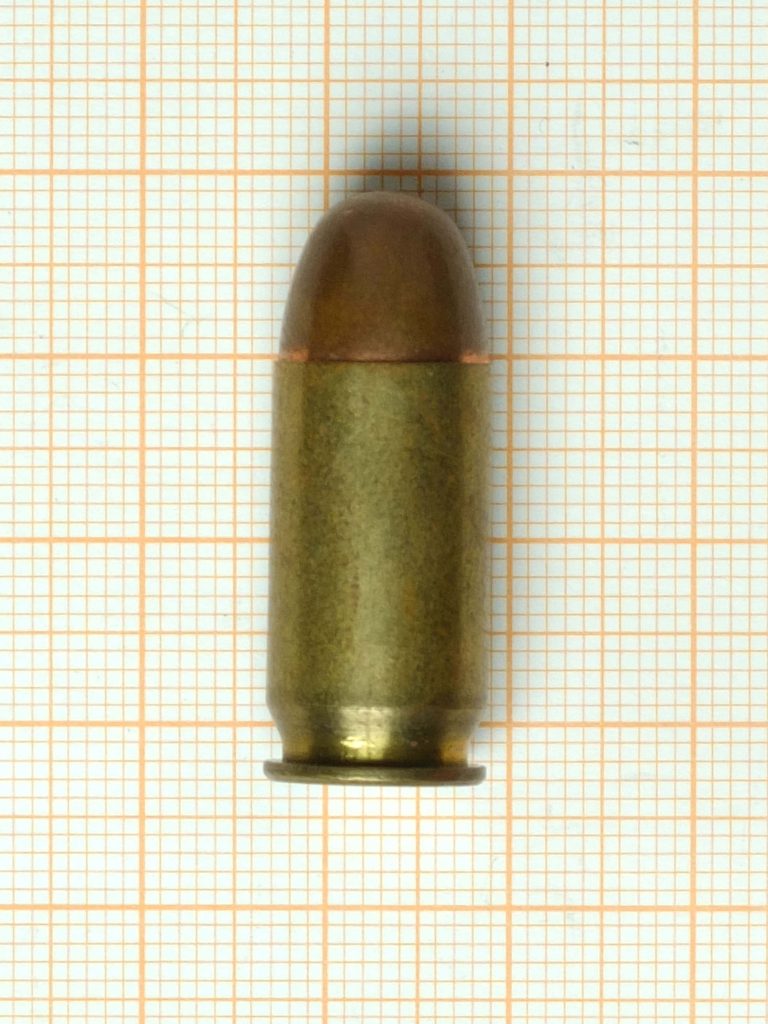 Single handgun cartridge with copper tip on orange grid paper industrial ammo wallpaper background
