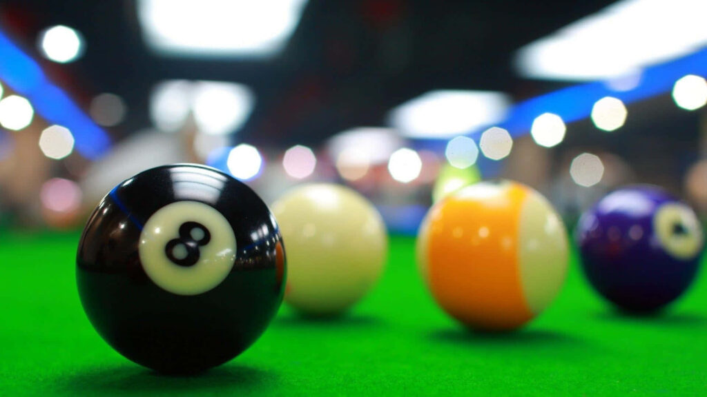 Close-up of iconic eight-ball on green billiards table with bokeh lighting and blurred pool balls Wallpaper