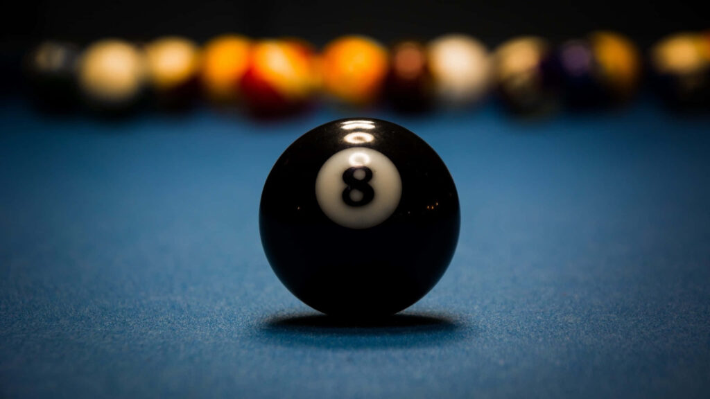 Sharp eight-ball wallpaper on blue pool table with blurred colorful billiard balls background