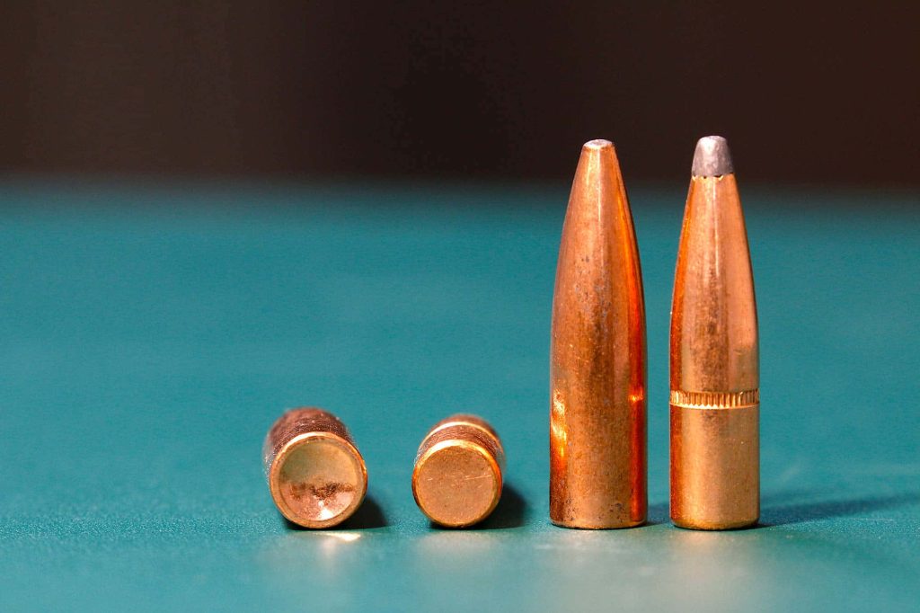 Macro photo of four copper-jacketed bullets on matte teal surface showing texture and design Wallpaper