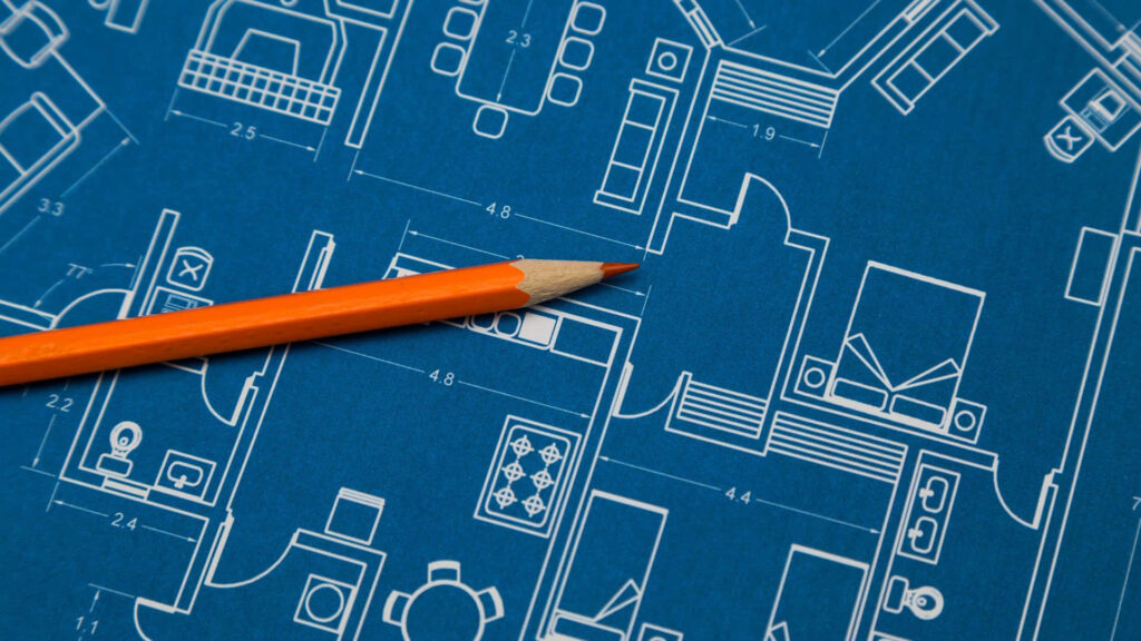 Sharp orange pencil on detailed architectural blueprint showcasing precision in building design Wallpaper
