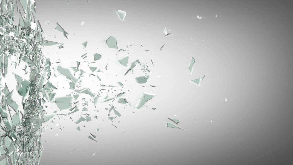 Close-up of shattered glass shards suspended mid-air with reflections on grey gradient background Wallpaper