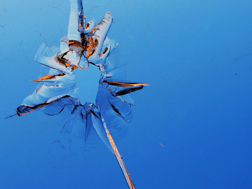 Shattered glass burst pattern on smooth blue background with sharp cracks and intricate details Wallpaper