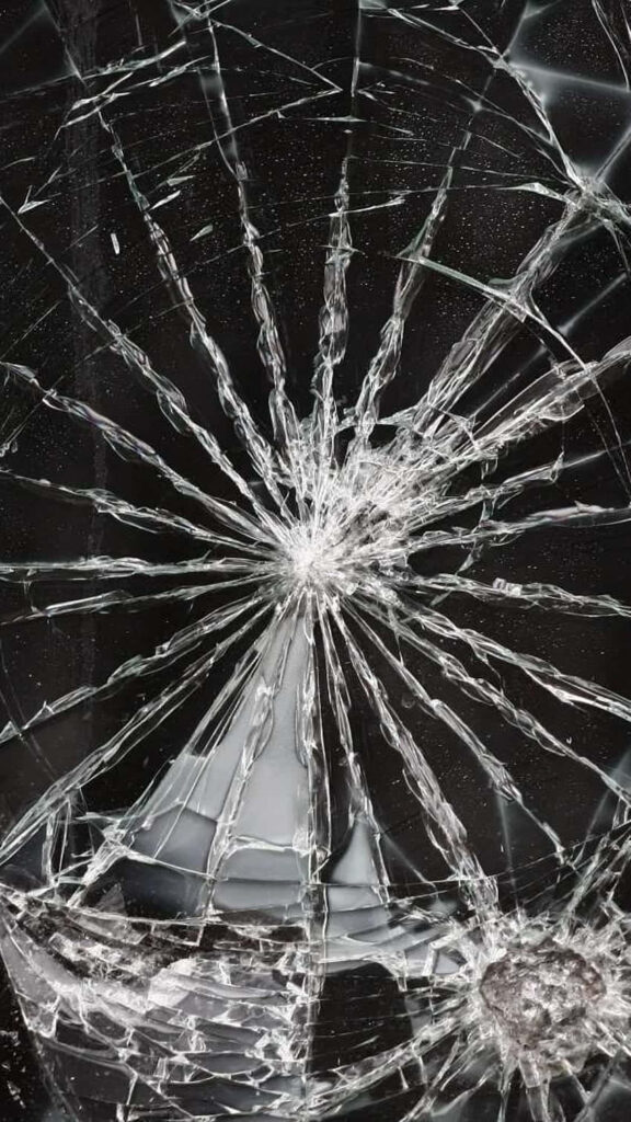 Shattered glass wallpaper with realistic spiderweb cracks on dark background for digital art