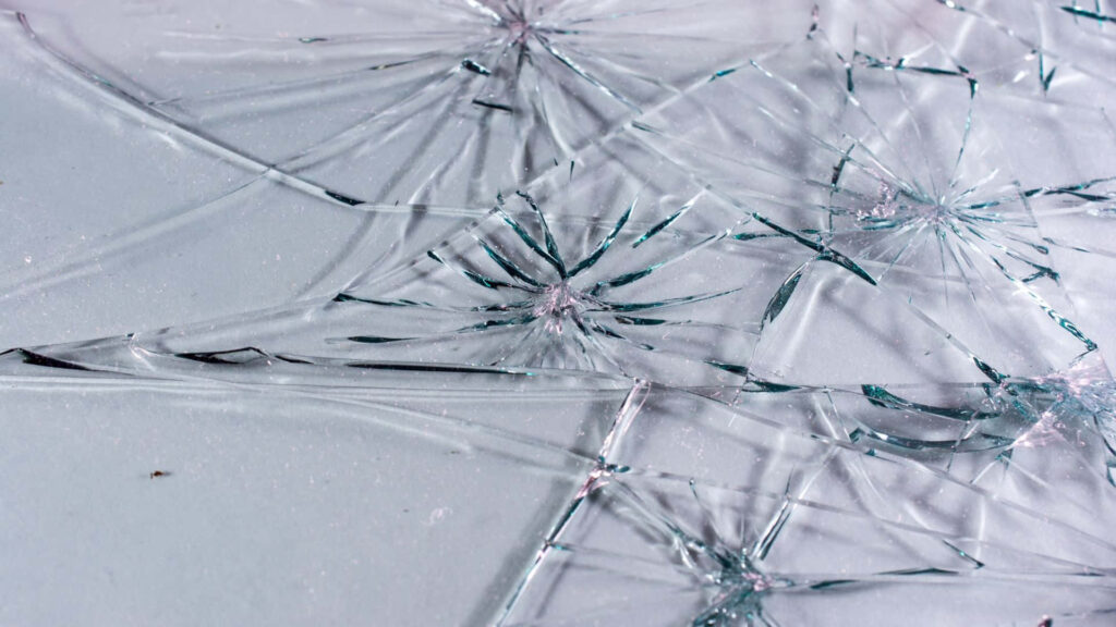 Intricate shattered glass pattern on black background with sharp broken glass shards wallpaper