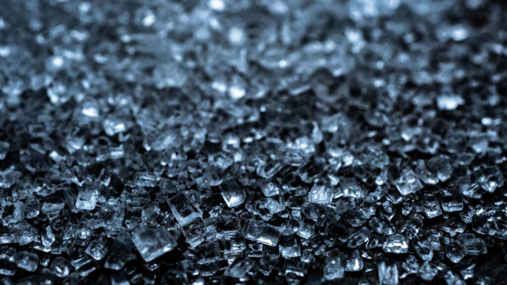 Close up of shattered glass fragments in blue tones with reflective surfaces abstract background Wallpaper