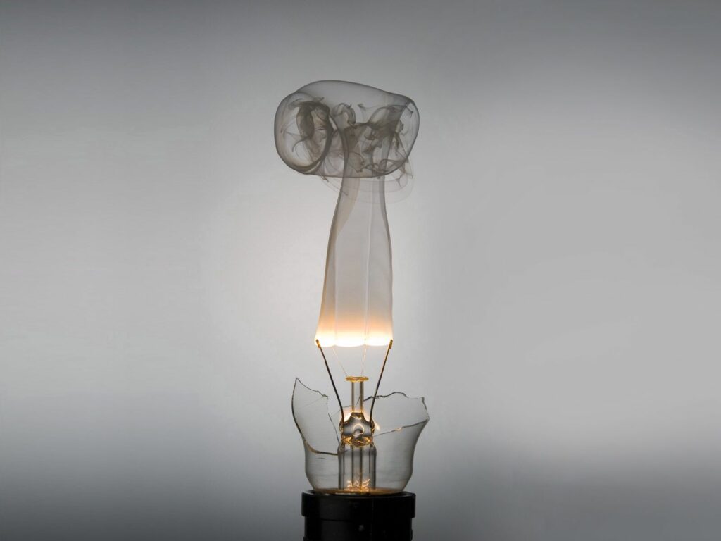 Artistic Shattered Light Bulb Wallpaper with Ethereal Smoke Patterns