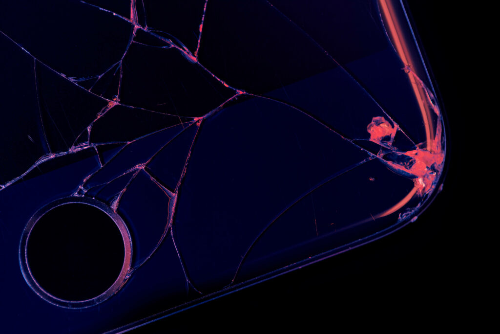 Close-up of shattered phone screen with neon purple and red cracks vibrant broken screen wallpaper