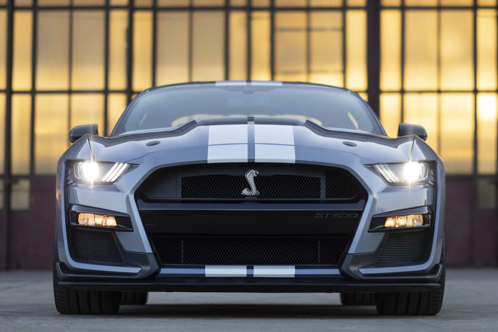 Shelby Mustang GT500 front view aggressive grille racing stripes illuminated headlights industrial background Wallpaper