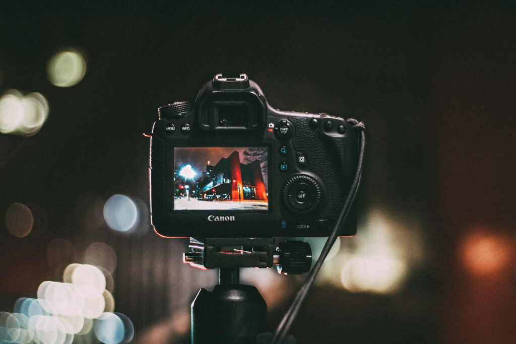 Focus and Bokeh: An Enchanting Capture of a DSLR Camera amidst a Stunning Background of Glowing Lights Wallpaper