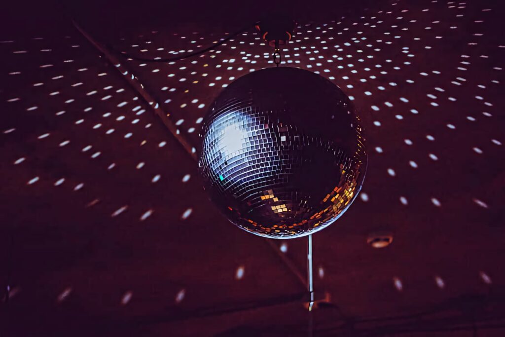 Shimmering disco ball casting radiant light specks on dark backdrop vibrant retro nightlife wallpaper