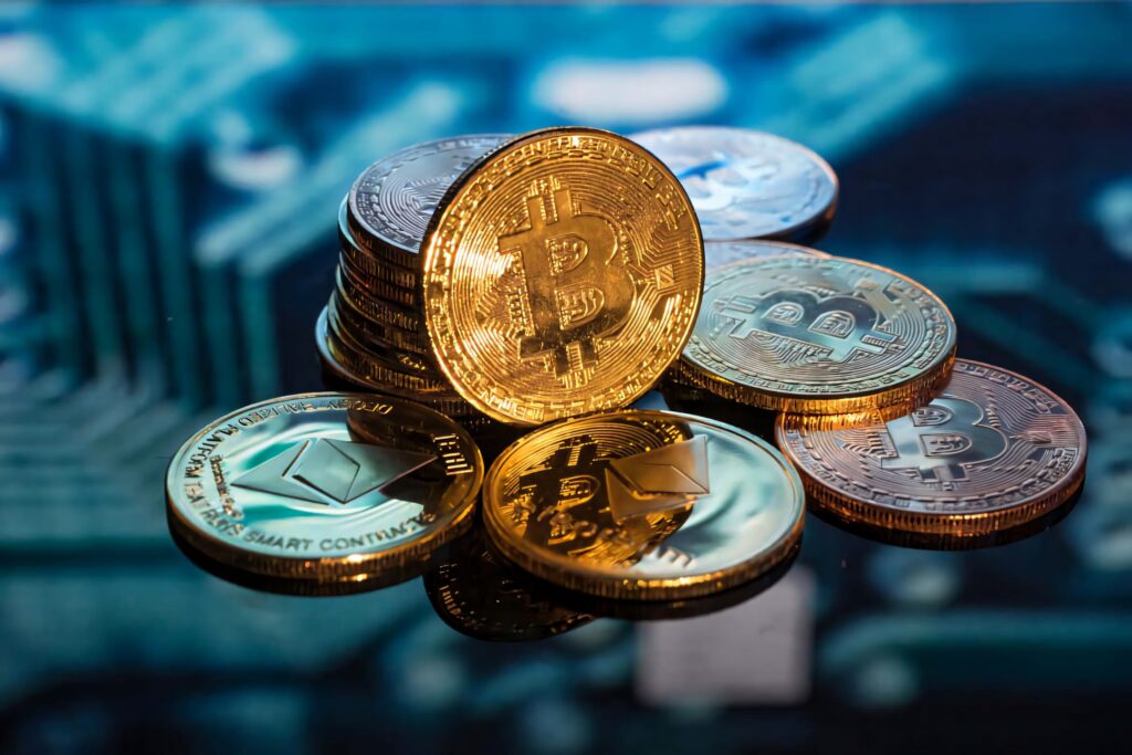Stack of shiny gold Bitcoin and Ethereum coins on reflective surface representing digital currency Wallpaper