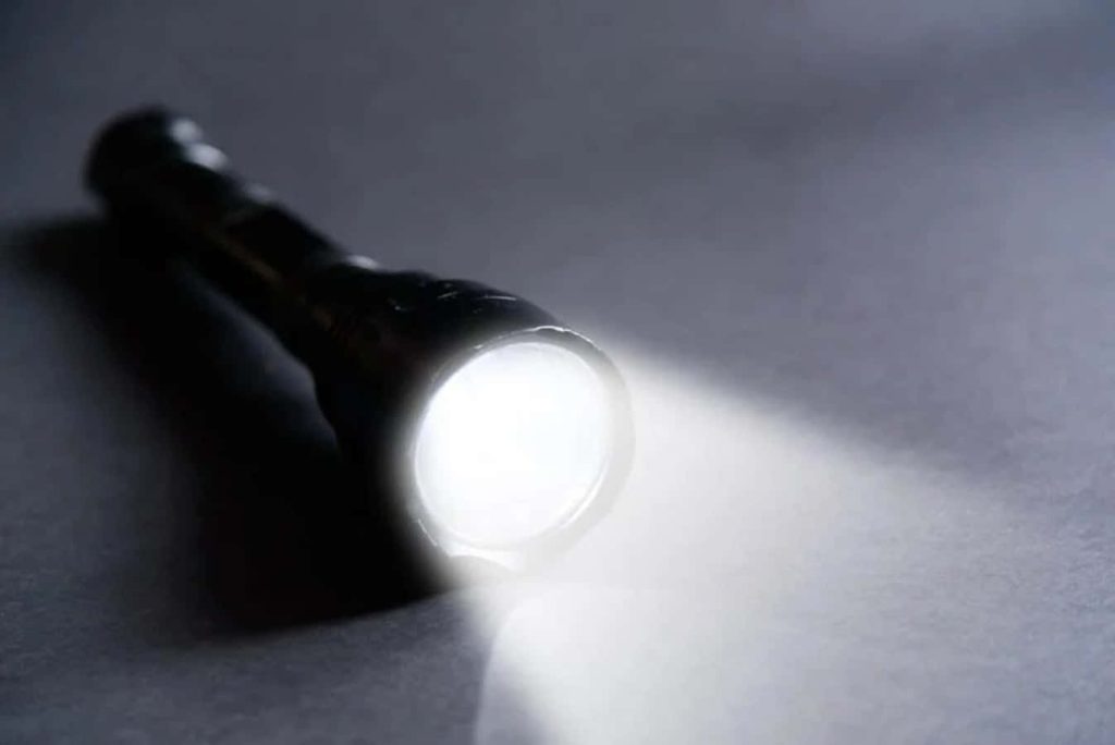 Flashlight shining bright white beam on dark textured background minimalist wallpaper