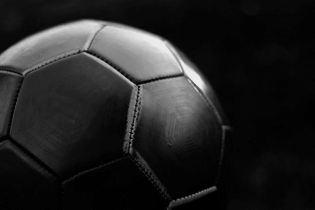 Close-up of a textured monochrome soccer ball with dramatic lighting on black background wallpaper