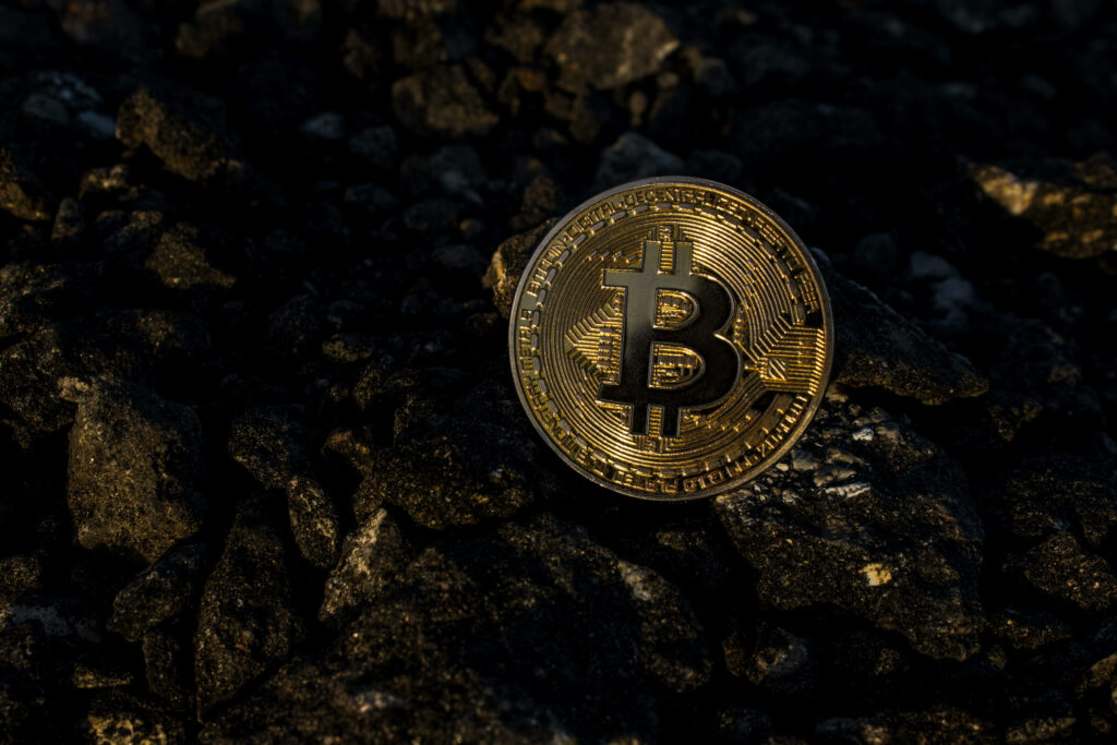 Shiny Bitcoin coin on dark rocky background symbolizing cryptocurrency in finance wallpaper