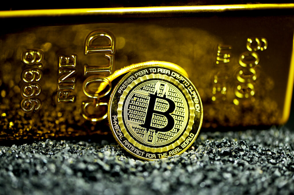 Shiny Bitcoin coin in front of gold bar on black surface symbolizing cryptocurrency wealth Wallpaper
