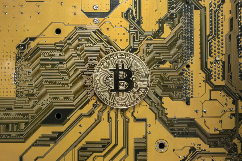 Shiny Bitcoin coin on gold motherboard symbolizing cryptocurrency and modern technology background Wallpaper