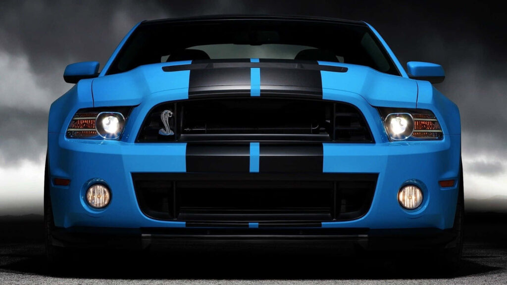 Shiny blue car with black racing stripes parked against dark dramatic background wallpaper