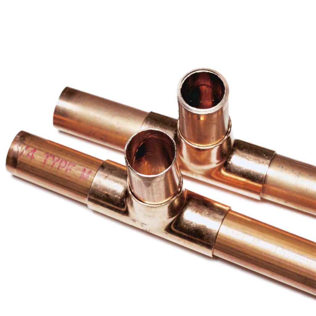 Close-up of shiny copper pipes with T-joints highlighting metallic sheen and warm tones Wallpaper