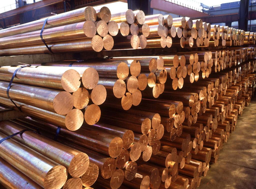 Stacked copper rods in warehouse with shiny metallic surfaces warm reddish brown industrial background Wallpaper