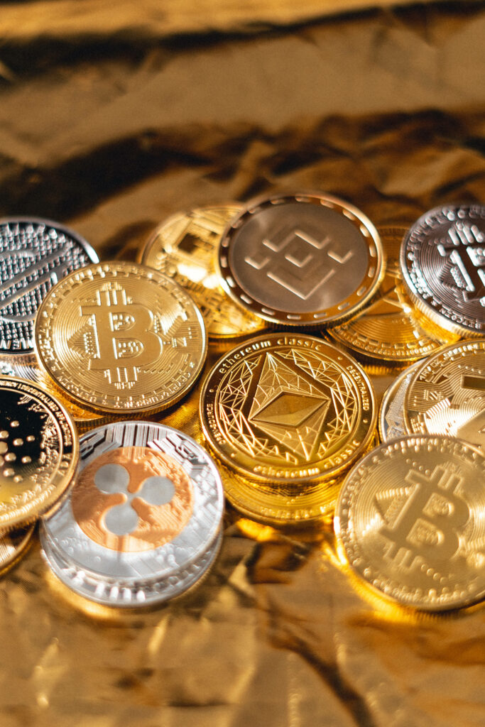 Shiny cryptocurrency coins including Bitcoin Ethereum Ripple on reflective gold surface wallpaper background