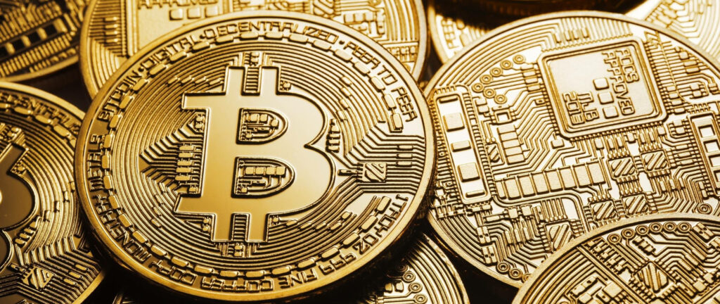 Close-up of shiny gold Bitcoins with Bitcoin symbol and circuit engravings crypto coins background Wallpaper