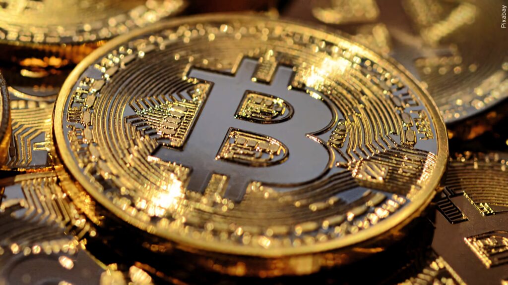 Close-up of shiny gold Bitcoin coin with intricate digital details and glowing reflective surface Wallpaper