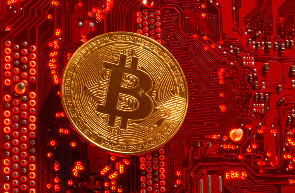 Shiny gold Bitcoin coin on vibrant red circuit board representing digital currency technology Wallpaper