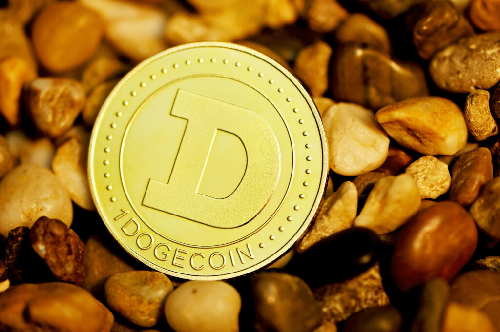 Shiny gold Dogecoin coin among colorful river stones close-up digital currency finance wallpaper