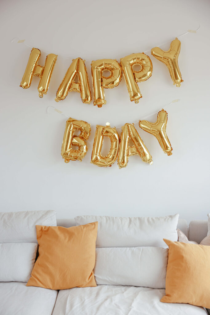 Shiny Gold Balloon Birthday Wallpaper with Cozy Couch Background