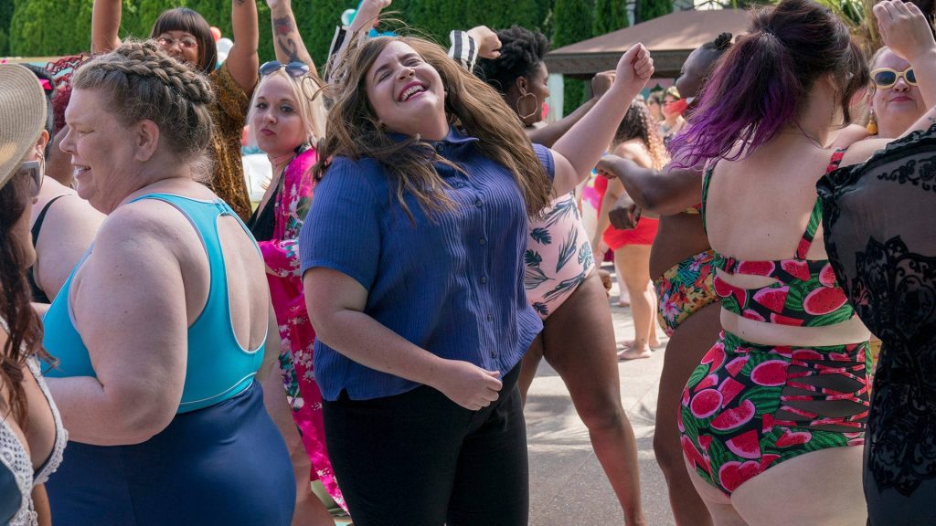Aidy Bryant dancing outdoors with diverse women at sunny party vibrant body positivity wallpaper