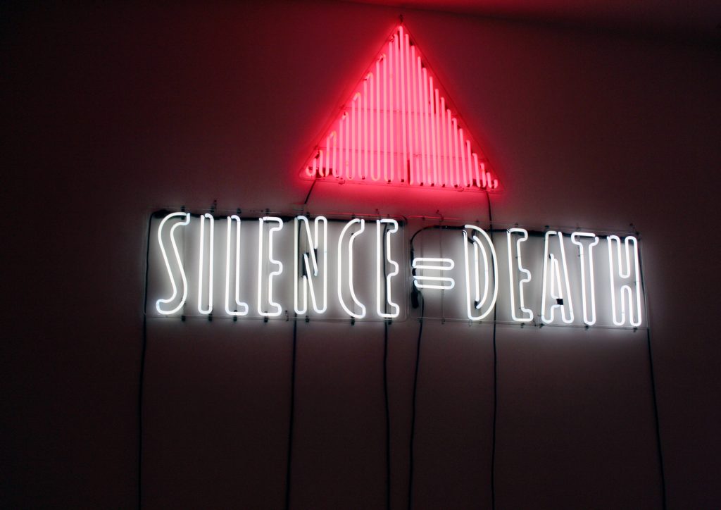 Neon Silence Equals Death sign with red triangle on dark background AIDS activism wallpaper